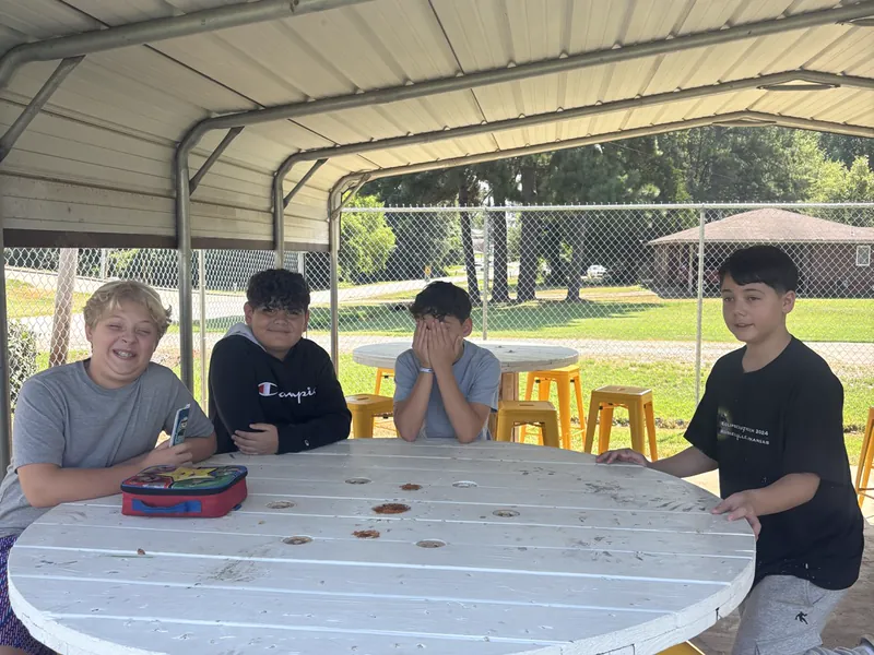 Students at a picnic table under the outdoor shelter