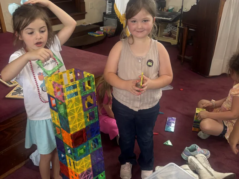 Two students with a tall tower they built from blocks