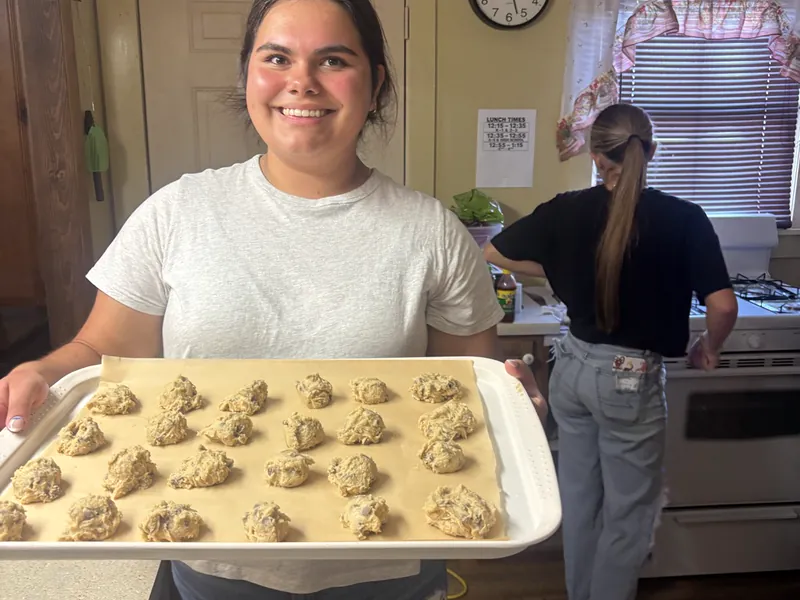 A student carrying a tray of cookies from a baking lesson