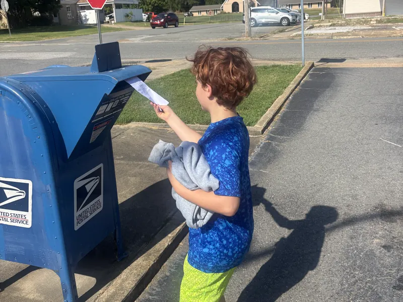 A student posting a letter on a walk into town