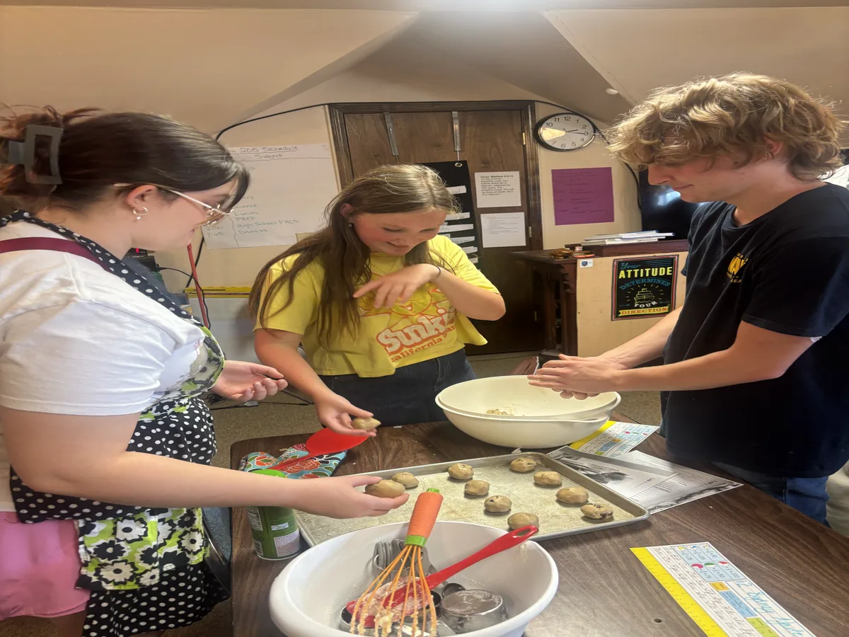 Students measuring and shaping cookie dough during a cooking lesson