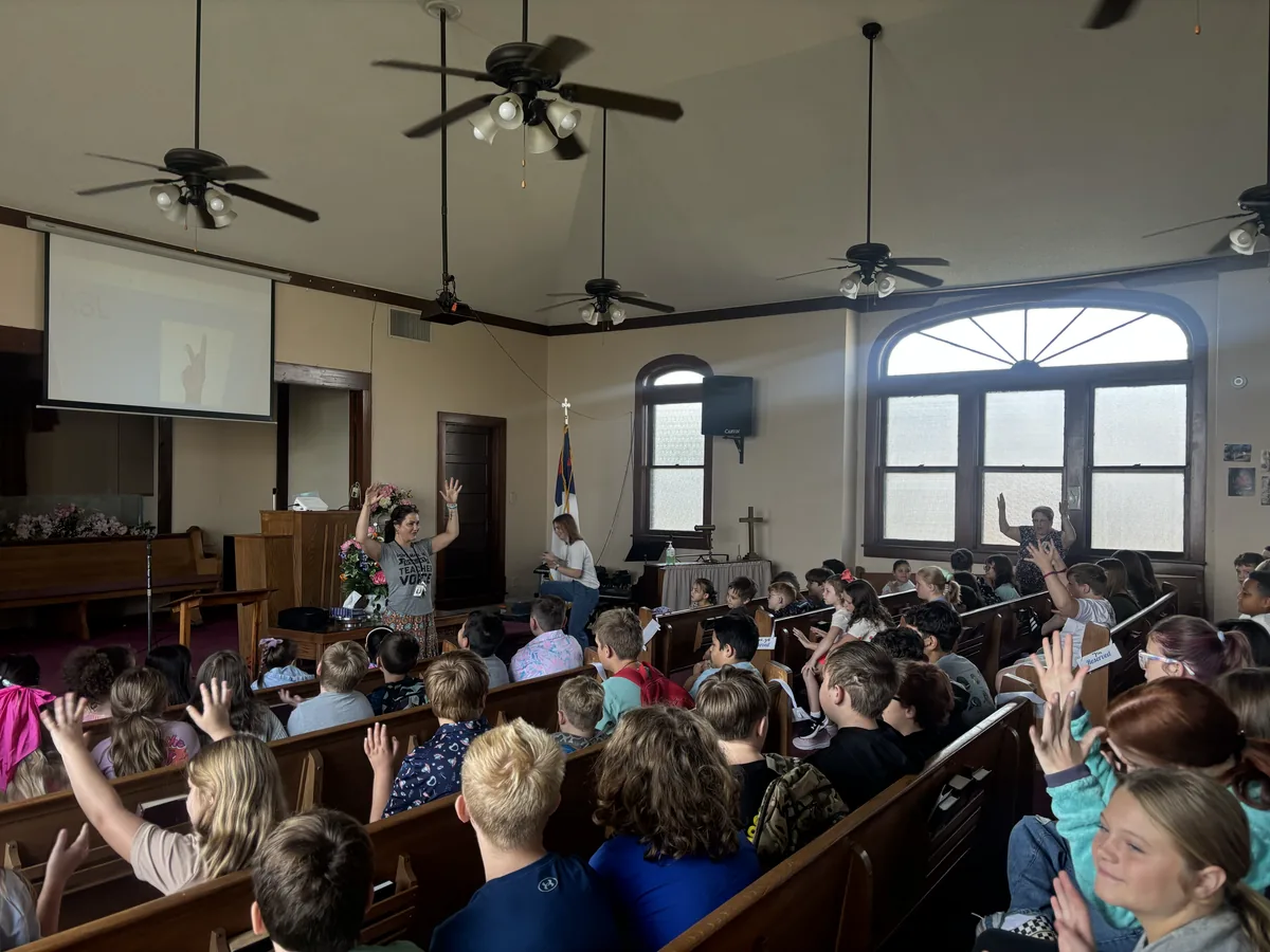 Students in the sanctuary during morning worship, many with hands raised