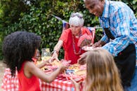 A vibrant family gathering outdoors with grandparents serving food at a picnic table.